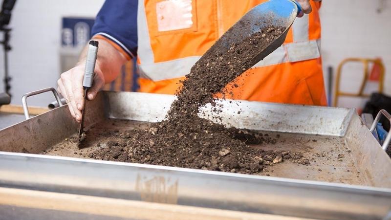 A geotechnical engineer in high-vis testing a soil sample using equipment in the RMA Soils + Geotechnical nata-endorsed laboratory