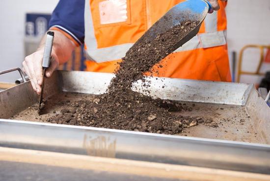 A geotechnical engineer in high-vis testing a soil sample using equipment in the RMA Soils + Geotechnical nata-endorsed laboratory